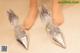 A pair of silver shoes with a bow on the toes.