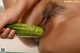 A woman is holding a cucumber in her mouth.