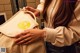 A woman holding a white bag with a yellow logo on it.